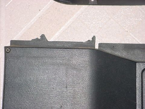 1983 Ford Bronco - Close-up of a dark gray textured plastic interior trim panel with a notched edge.