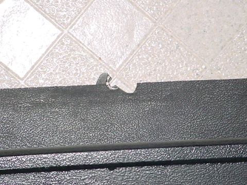 1983 Ford Bronco - Detail of a black textured interior trim piece, possibly from a vehicle, with a visible metal clip mechanism.