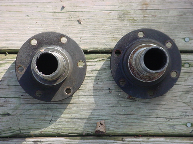 Two metal wheel hubs with bolt holes and splined centers sit on a wooden surface