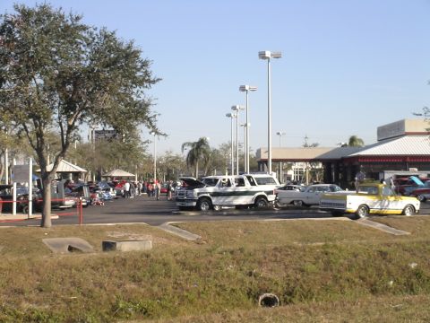 1993 Ford C-350 (Centurion Conversions) - A white and green van is parked at an outdoor event with several other cars.