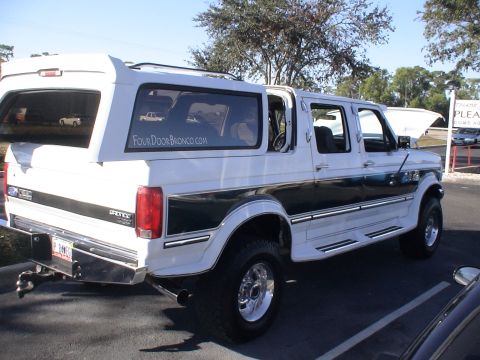 1993 Ford C-350 (Centurion Conversions) - This white four-door Bronco conversion features dark green and chrome trim, with a "FourDoorBronco.com" sticker visible on the rear window.