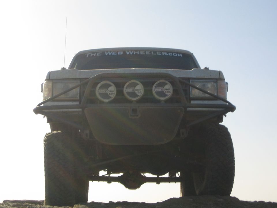 Low-angle front view of lifted truck against bright sky with tube bumper and three lights