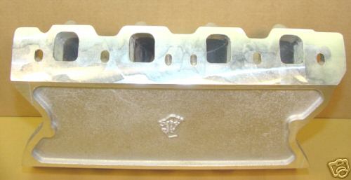 Cast aluminum engine part with four rectangular ports and a smaller machined surface on yellow background