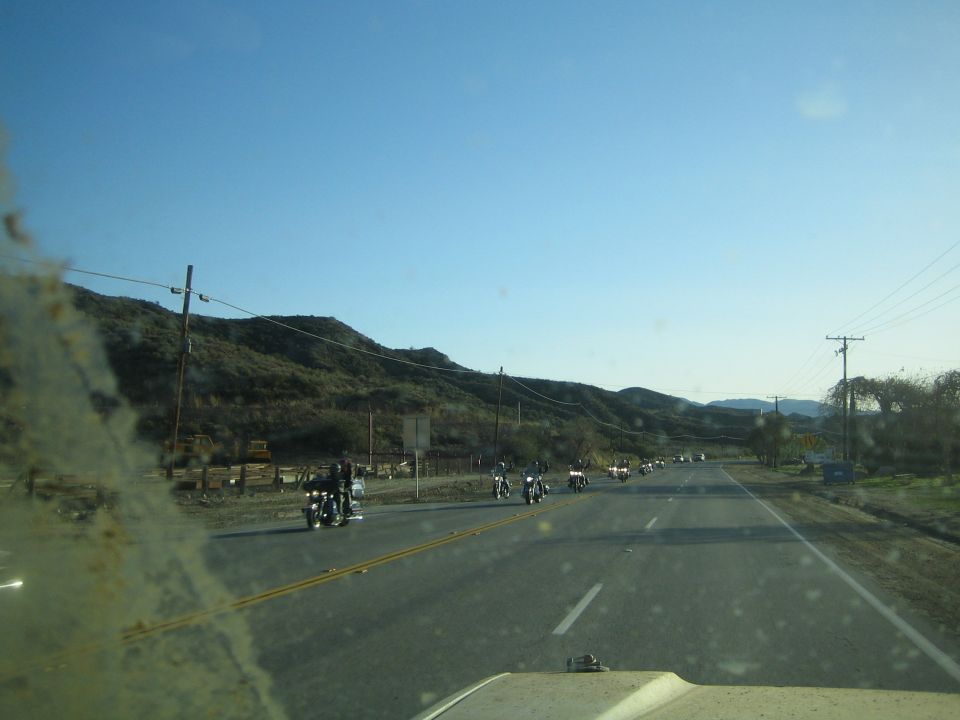 View through a windshield of motorcycles riding along a rural highway by hills