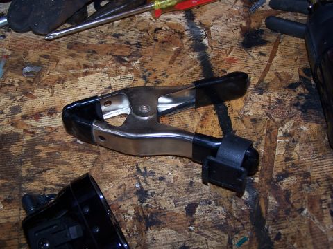 1986 Ford Bronco - A close-up view of a jumper cable clamp resting on a wooden surface alongside various tools.