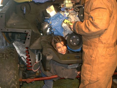 1978 Ford Bronco - Child helps with engine work, peeking from the engine bay while an adult makes adjustments.