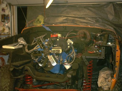1978 Ford Bronco - The engine bay of a vehicle is shown, with the engine and various components visible under a tarp.
