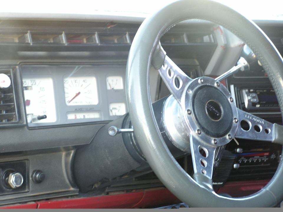 Dashboard with aftermarket chrome steering wheel, white gauge cluster, and aftermarket stereo
