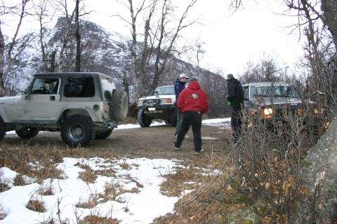 2003 Jeep TJ - A group of off-road enthusiasts gather their vehicles on a snowy trail, with a mountain peak visible in the distance.
