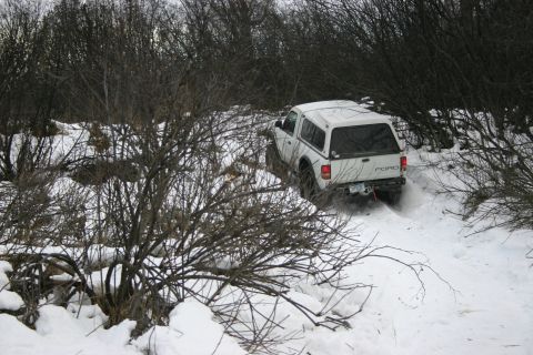 2003 Jeep TJ - A white 2003 Ford pickup truck navigates a snow-covered trail, kicking up snow as it drives.