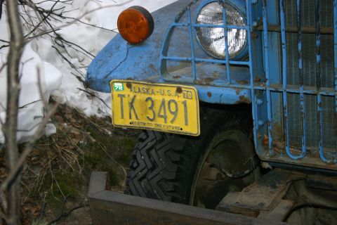 2003 Jeep TJ - A blue truck with an Alaska license plate sits in a snowy, wooded area.