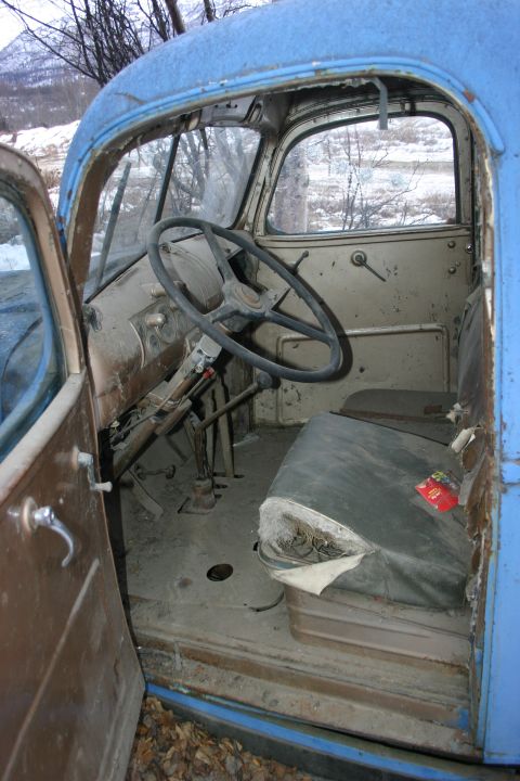 2003 Jeep TJ - The interior of an old blue truck cab, a worn steering wheel and a damaged driver's seat.