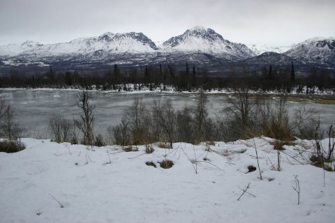 2003 Jeep TJ - A winter scene features snow-covered mountains overlooking a frozen river and barren trees.