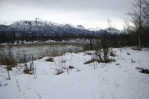 2003 Jeep TJ - Winter scene snow-covered ground, a frozen river, and distant mountains under a cloudy sky.