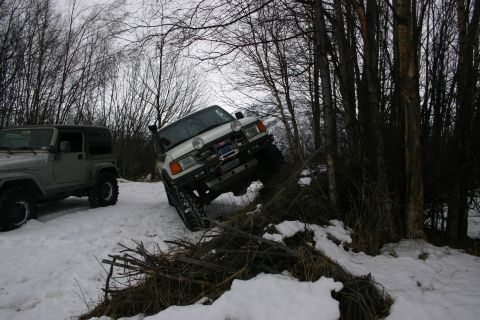 2003 Jeep TJ - Two off-road vehicles navigate a snowy trail surrounded by trees.