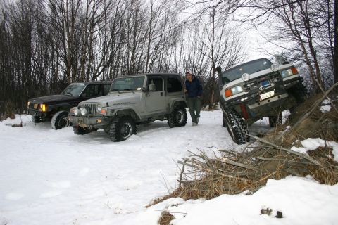 2003 Jeep TJ - Three off-road vehicles are parked in a snowy area with trees in the background.