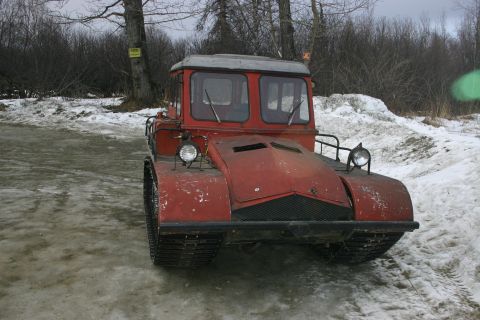 2003 Jeep TJ - A red tracked vehicle sits in a snowy landscape, its tracks visible on the ground.