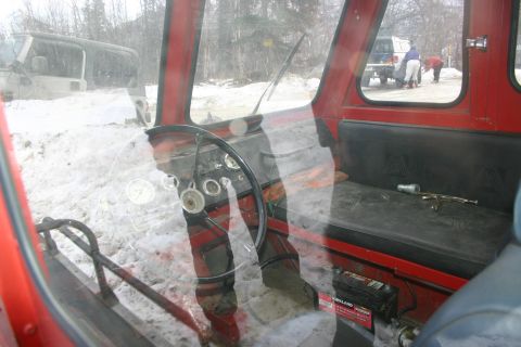 2003 Jeep TJ - Interior of a red vehicle with a steering wheel and gauges, with another Jeep visible outside.
