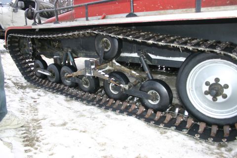 2003 Jeep TJ - The track system of a snow vehicle, showing its rollers and rubber track, with another vehicle in the background.