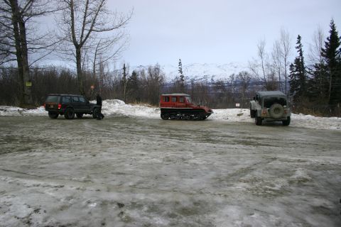 2003 Jeep TJ - A gray Jeep CJ-7 is viewed from the rear on a snowy and icy surface with mountains in the background.
