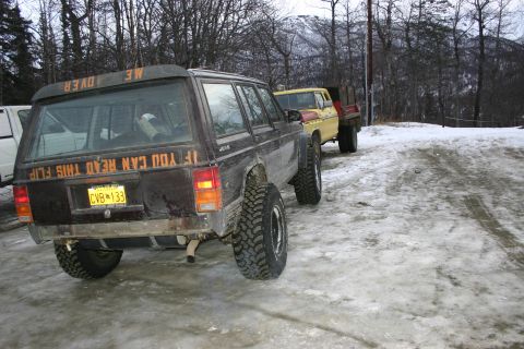 2003 Jeep TJ - Jeep Cherokee XJ and a pickup truck parked on a snowy, icy surface with trees in the background.