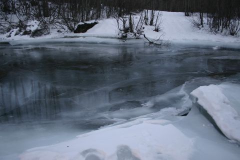 2003 Jeep TJ - A frozen river scene with ice and snow, surrounded by bare trees under a winter sky.