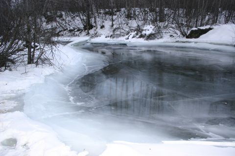 2003 Jeep TJ - A winter scene shows a partially frozen river with ice formations along the bank and snow-covered trees in the background.