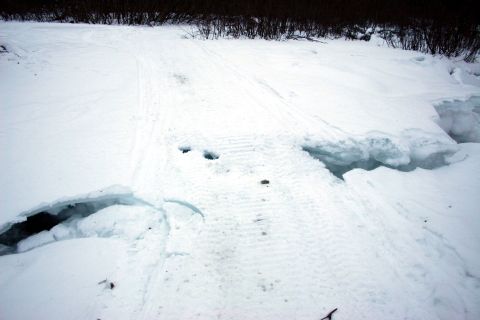 2003 Jeep TJ - A winter scene shows snow-covered ground with tire tracks leading towards a large, broken ice formation.