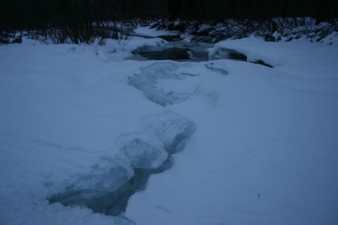 2003 Jeep TJ - A winter scene shows a partially frozen stream with large cracks in the ice and snow-covered banks.