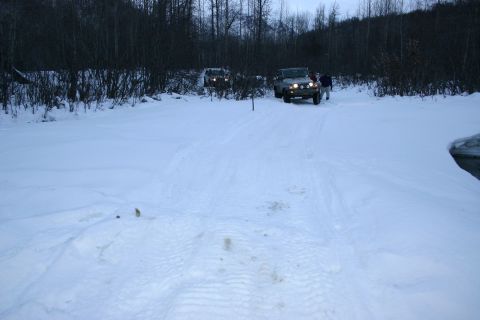 2003 Jeep TJ - Two SUVs navigate a snowy trail surrounded by trees during daylight.