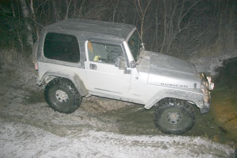 2003 Jeep TJ - A silver Jeep Wrangler Rubicon is parked on a muddy, snowy trail next to trees.