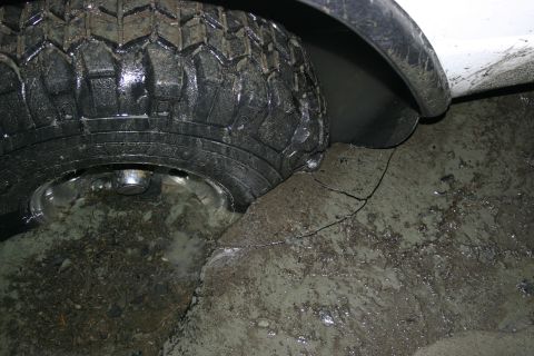 2003 Jeep TJ - A close-up view of a vehicle's tire and fender, partially submerged in mud and water.