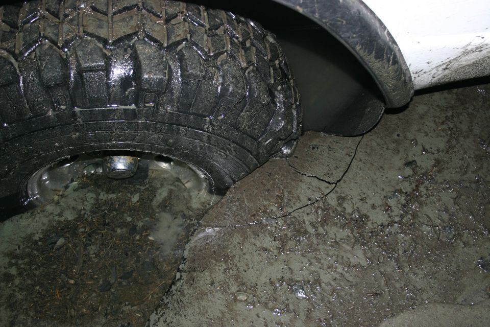 Close-up of a muddy tire and white fender of a vehicle