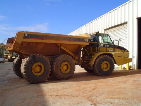 1966 International School Bus - A yellow Caterpillar articulated dump truck, model 740, is parked in front of a white building.