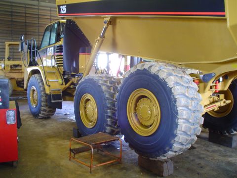 1966 International School Bus - CAT articulated dump truck parked indoors, with another vehicle in the background.