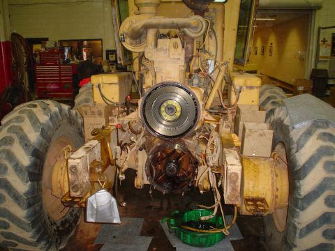 1966 International School Bus - The engine and drivetrain of a yellow heavy equipment vehicle are disassembled for service.