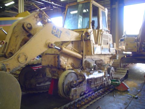 1966 International School Bus - Yellow Caterpillar bulldozer with tracks and a front loader is parked inside a building.