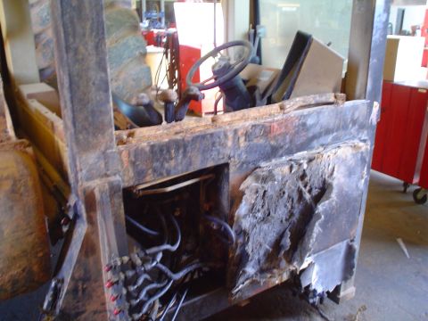 1966 International School Bus - The interior of a forklift shows significant damage and exposed hydraulic lines.