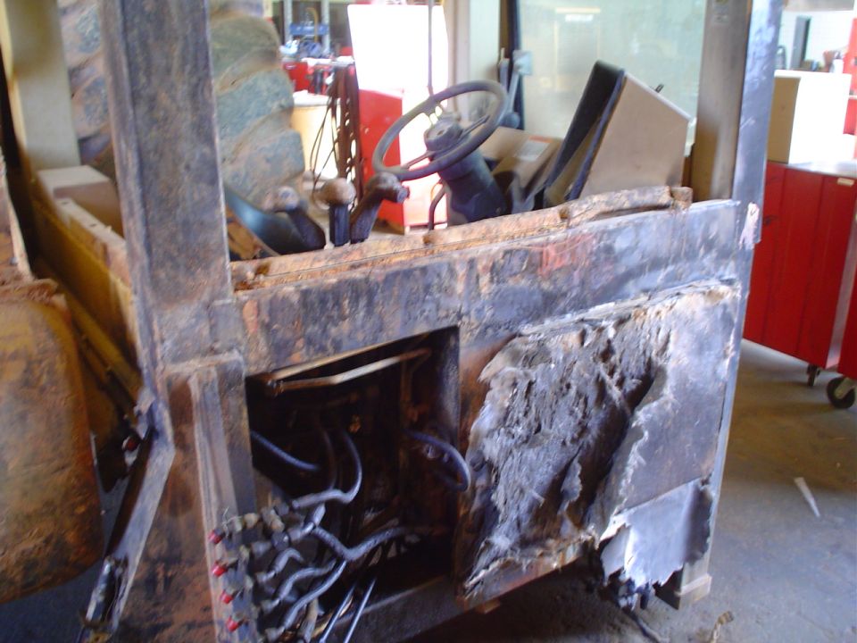 Damaged forklift interior with exposed wires and rusted metal