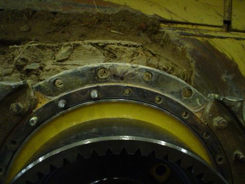 1966 International School Bus - Detail of gears and bolted flange on heavy machinery, obscured by dirt and debris.