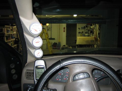 1994 Ford Bronco - The interior of a vehicle shows a cluster of gauges on the A-pillar and a cell phone mounted to the dash.