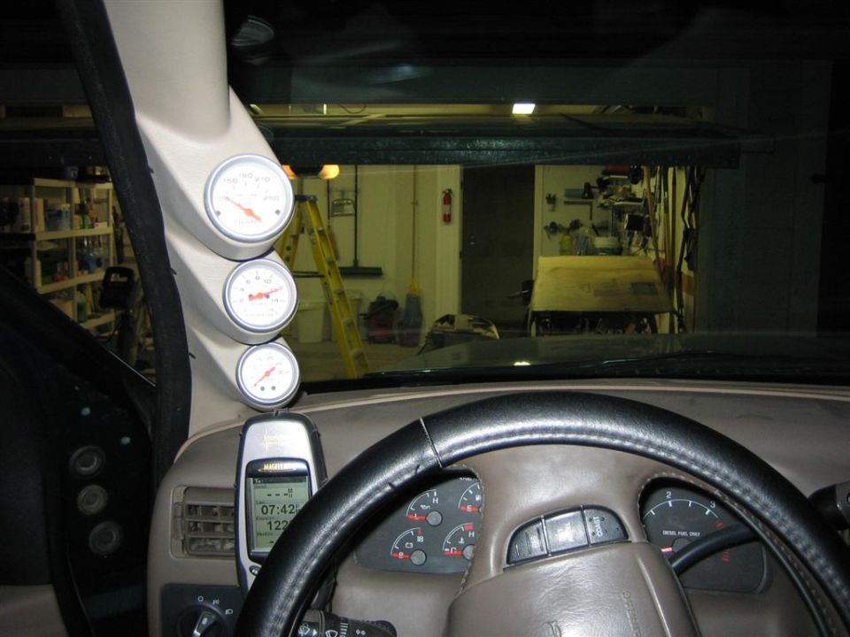 Dashboard with three gauges mounted on the A-pillar, a cell phone, and the steering wheel
