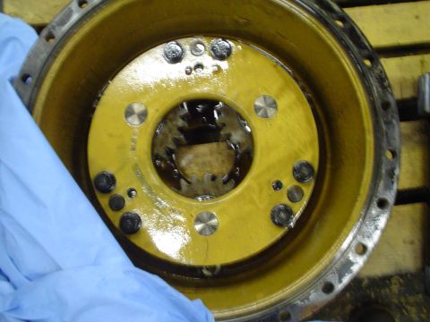 1966 International School Bus - A close-up view of a yellow metal component, possibly a differential or hub assembly, showing internal gears and bolt pattern.