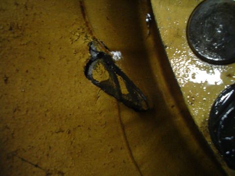 1966 International School Bus - Detail of yellow painted metal with a hole and two dark circular fasteners visible.