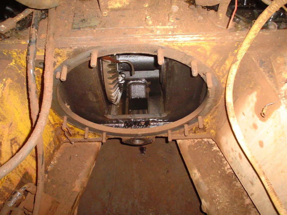 Rusty yellow metal housing with an oval opening revealing black gears and mechanical parts