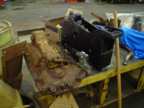 1966 International School Bus - A heavily rusted transmission and a black engine component are displayed on a workbench, suggesting a repair or restoration project.
