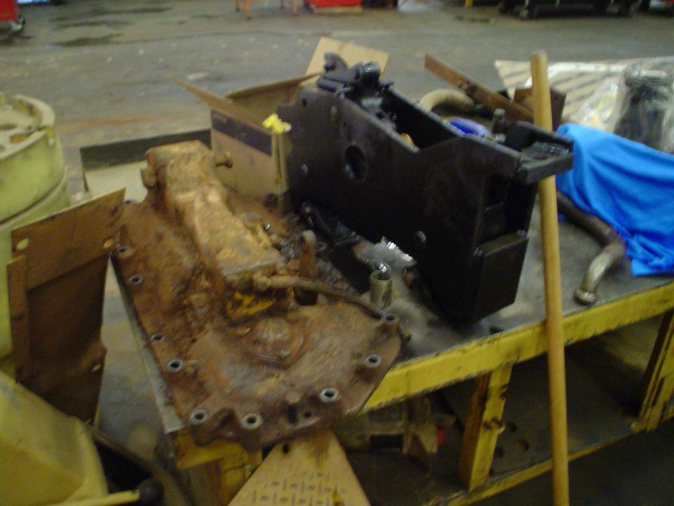 Rusted transmission and black engine part on a yellow workbench