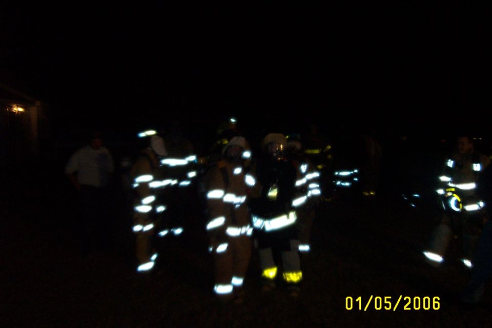 Firefighters in reflective gear at night with date 01/05/2006 visible