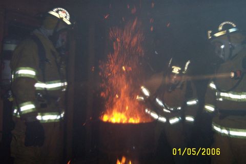1998 Ford Crown Victoria - Firefighters observe a fire, with sparks rising from the flames. The date 01/05/2006 is visible.