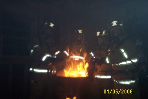 1998 Ford Crown Victoria - Firefighters are seen in protective gear around a burning fire pit, with the date 01/05/2006 visible.